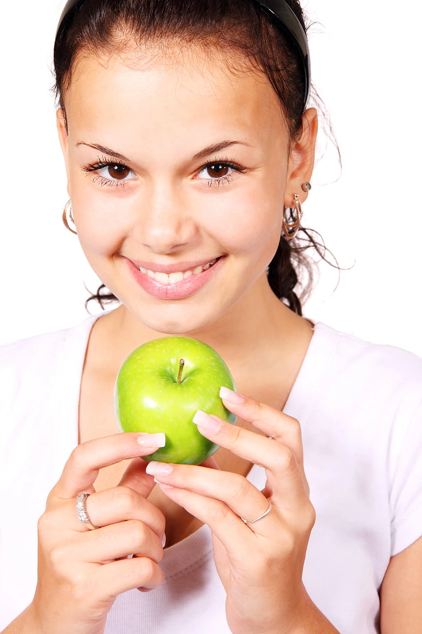 Smiling Woman Holding Green Apple on White Background