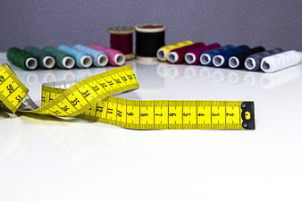 Yellow Tape Measure And Colorful Thread Spools On White Surface