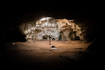 Woman standing in a large illuminated cave interior