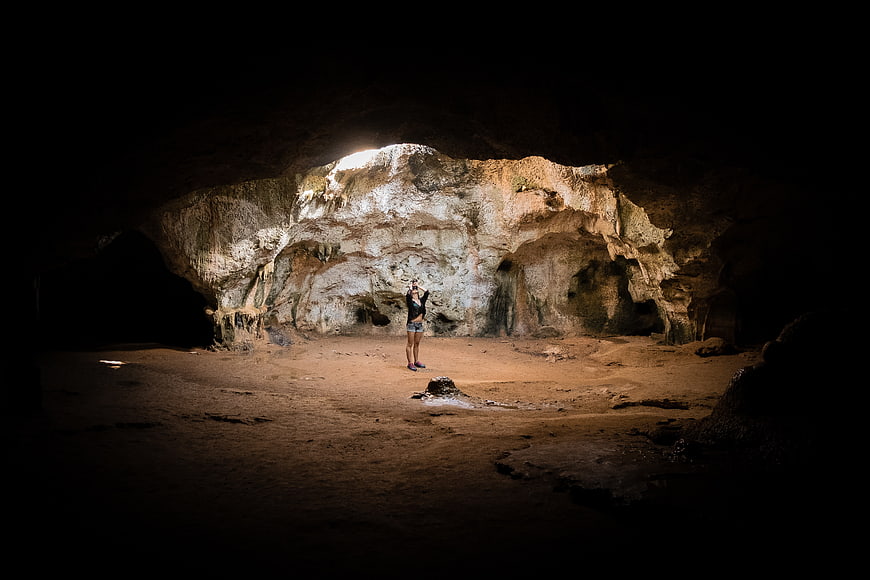 Woman standing in a large illuminated cave interior