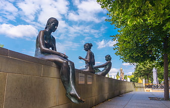 Bronze Sculptures of Women Sitting on a Wall in Berlin