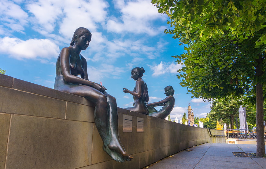 Bronze Sculptures of Women Sitting on a Wall in Berlin