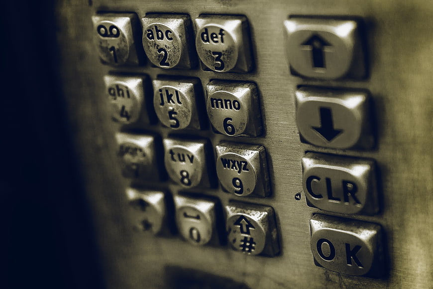 Close-up of vintage metallic telephone keypad with worn buttons