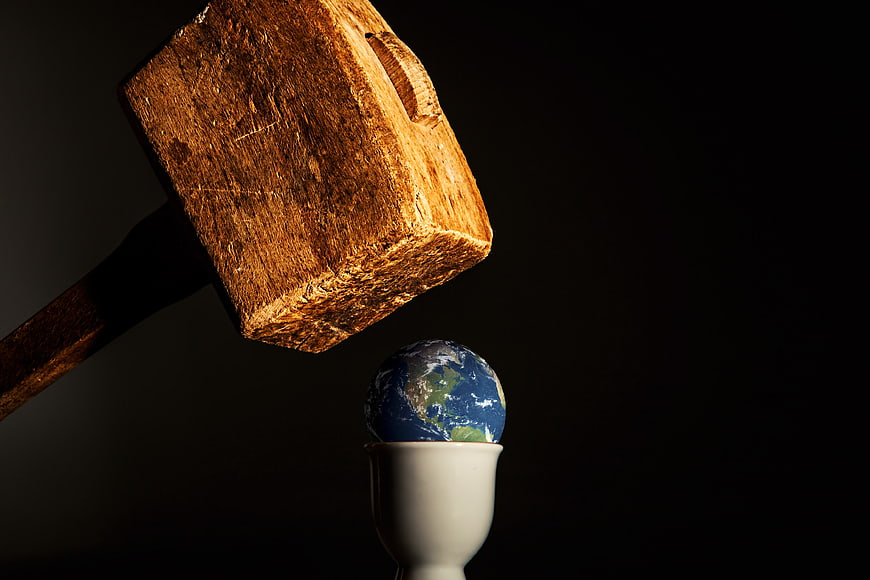 Wooden mallet striking globe in egg cup concept