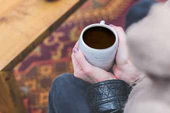 Woman holding warm coffee mug in cozy hands