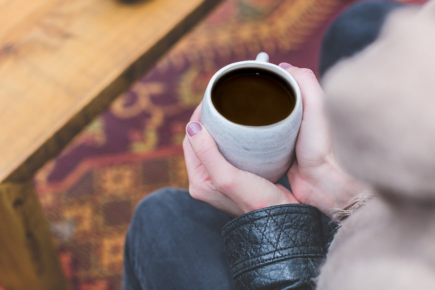 Woman holding warm coffee mug in cozy hands