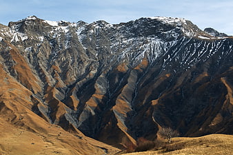 Dramatic Mountain Landscape with Snow-Capped Peaks and Golden Slopes