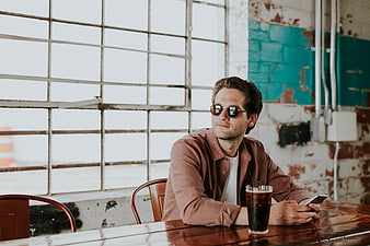 Man with sunglasses sitting at cafe table with iced coffee
