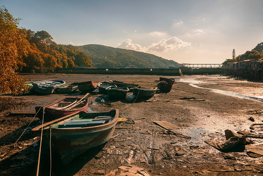 Weathered wooden boats resting on muddy riverbank at sunset