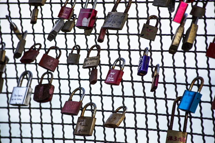 Colorful love padlocks attached to a metal fence grid