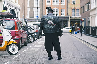 Man in Leather Jacket Walking Down Urban Street