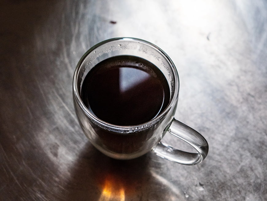 Top View of Black Coffee in Clear Glass Mug on Metal Surface