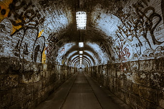 Graffiti Covered Arched Tunnel With Overhead Lights