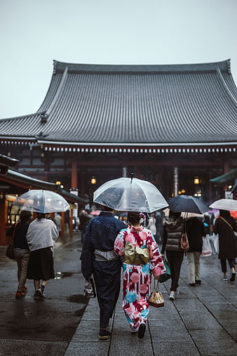 Couple in Kimonos Walking Under Umbrellas at Japanese Temple