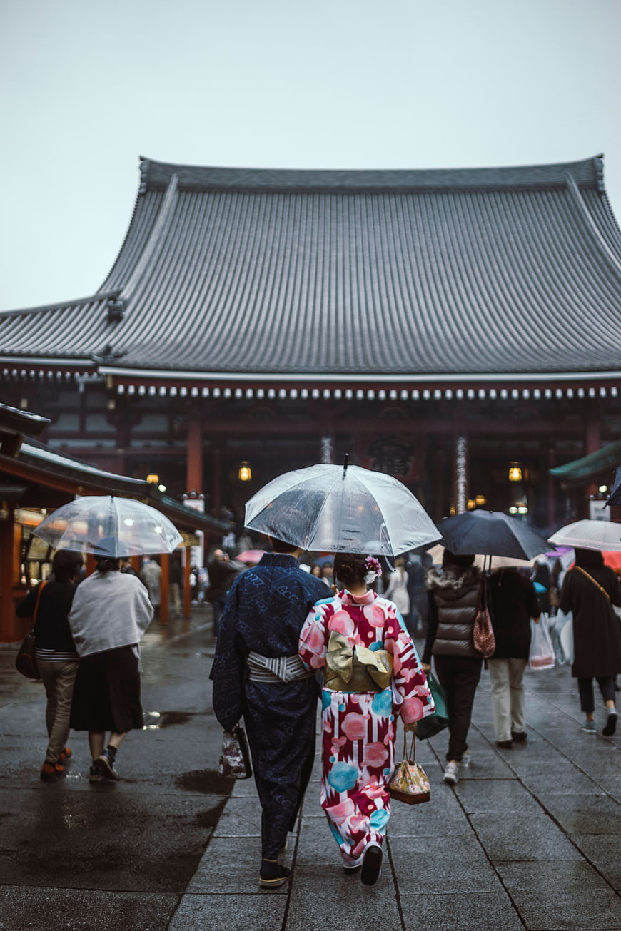 Couple in Kimonos Walking Under Umbrellas at Japanese Temple
