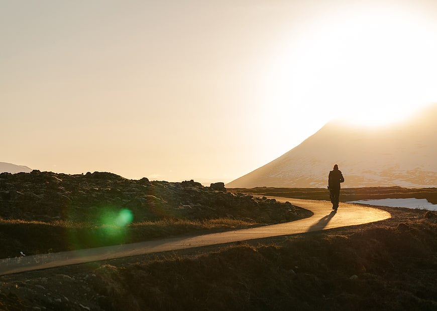 Silhouette of Hiker Walking on Road at Sunset
