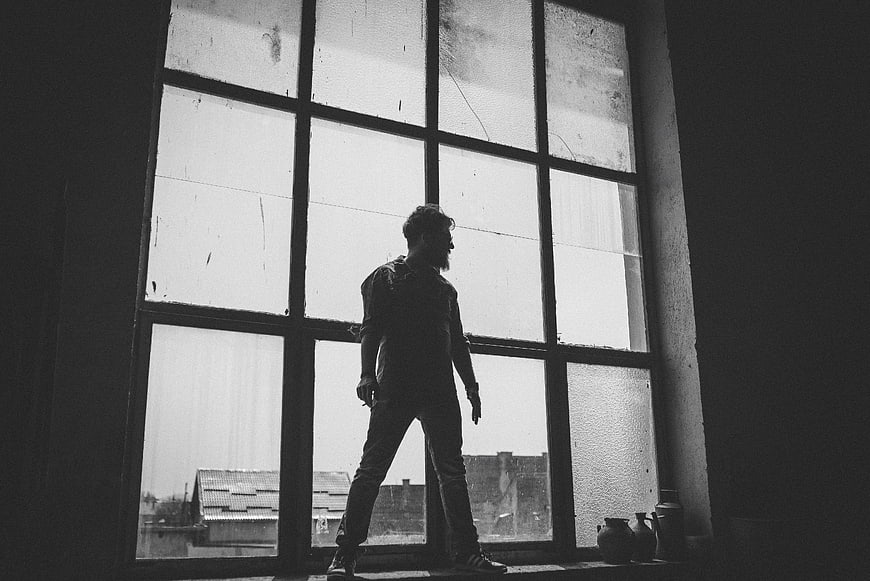 Silhouette of Man Standing in Large Industrial Window