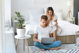Young couple relaxing in bedroom using laptop together