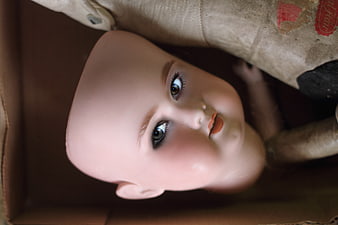 Close-up of vintage bald doll face in cardboard box