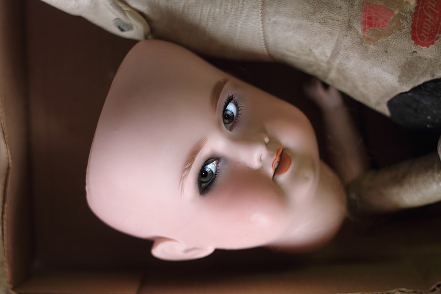 Close-up of vintage bald doll face in cardboard box