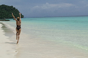 Woman running on tropical beach with turquoise water