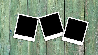 Three empty polaroid frames on rustic green wooden background