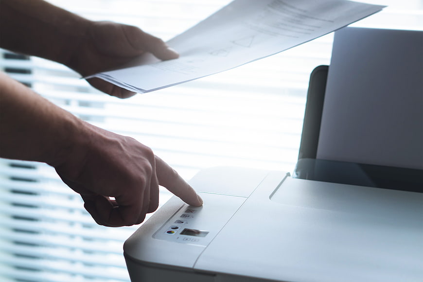 Hands pressing button on office printer with document