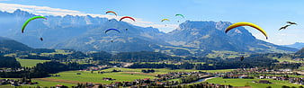 Colorful Paragliders Flying Over Alpine Valley Panorama