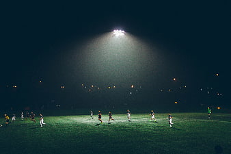 Soccer players on a field under bright stadium lights at night