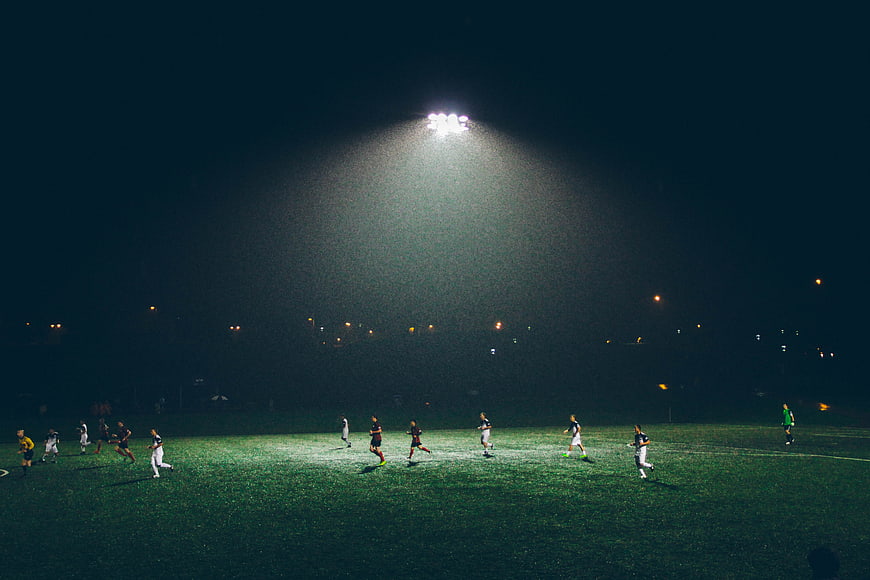 Soccer players on a field under bright stadium lights at night