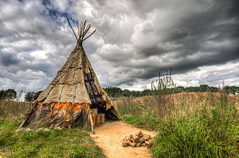 Historic Teepee in Field Under Dramatic Cloudy Sky