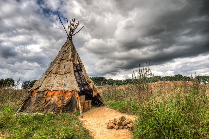 Historic Teepee in Field Under Dramatic Cloudy Sky