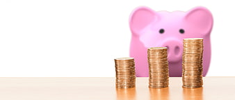 Stacks of coins and pink piggy bank on wooden table