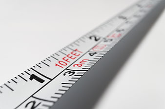 Close-up of measuring tape showing feet and meters on white background