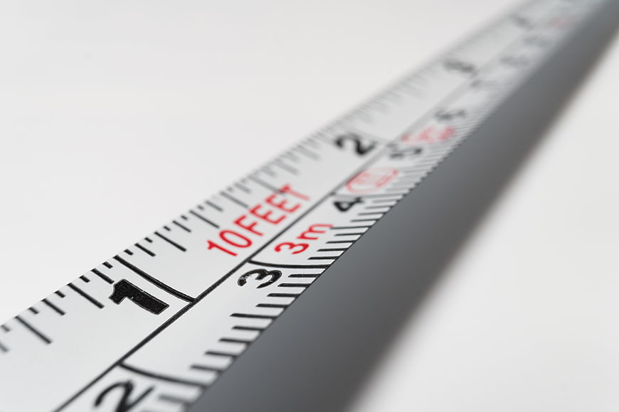 Close-up of measuring tape showing feet and meters on white background