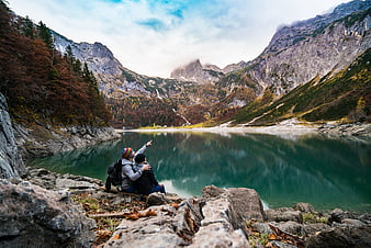 Couple of Hikers Pointing at Mountain Lake in Autumn