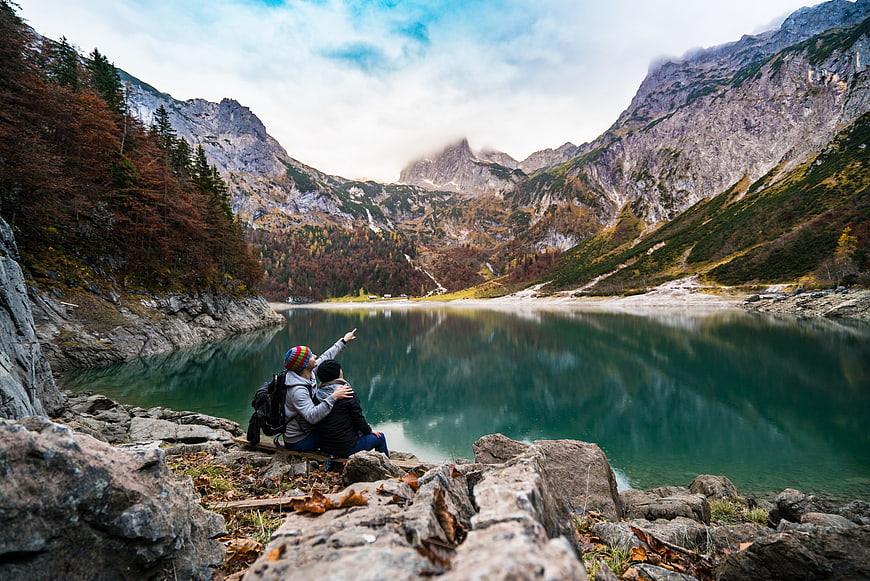 Couple of Hikers Pointing at Mountain Lake in Autumn