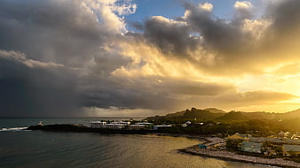 Dramatic sunset over coastal town with golden clouds and ocean
