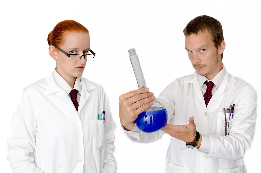 Two scientists in lab coats examining blue chemical liquid