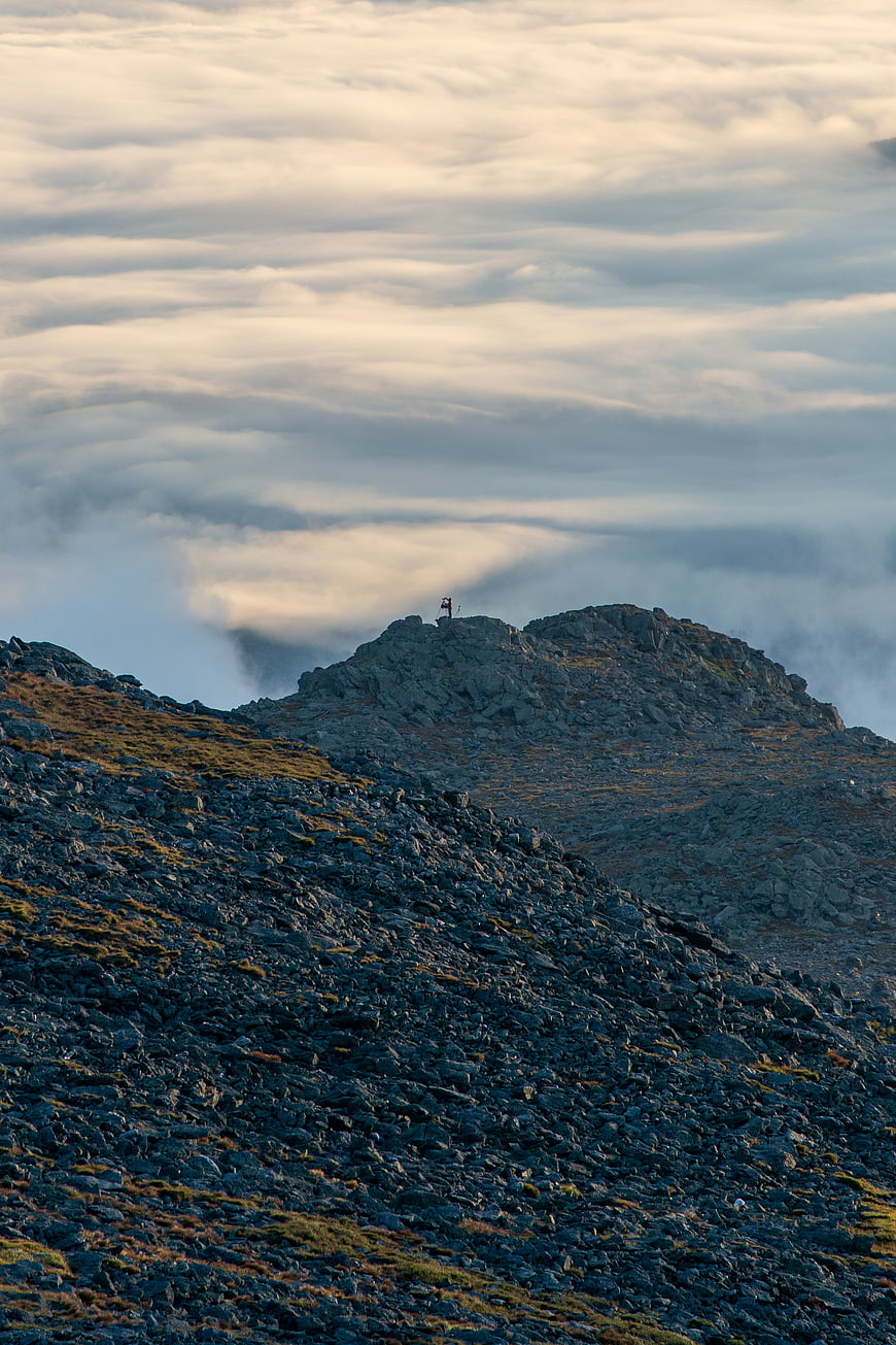 Hiker on Rocky Mountain Peak Above Sea of Clouds
