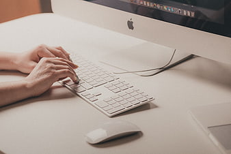 Hands typing on white keyboard at modern office desk