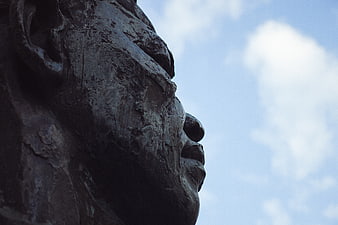 Close-up profile of bronze statue against blue sky