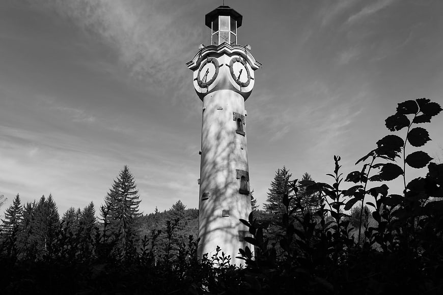 Black and white lighthouse clock tower in forest