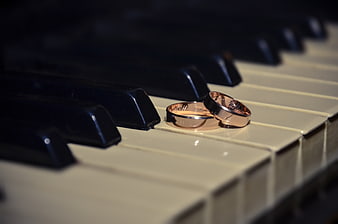 Two gold wedding rings resting on a piano keyboard