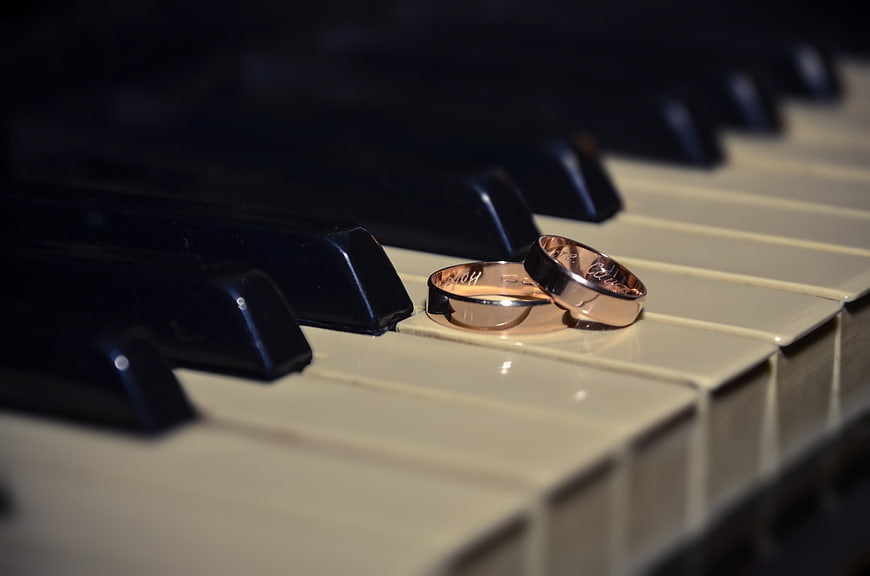 Two gold wedding rings resting on a piano keyboard