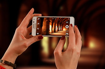 Woman holding white smartphone taking photo of architecture