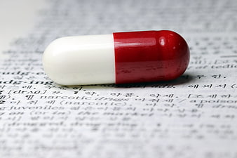 Red and white capsule pill on dictionary page