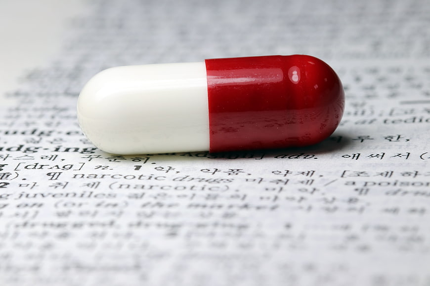Red and white capsule pill on dictionary page