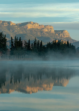 Misty Morning Lake with Mountain Reflections and Pine Trees