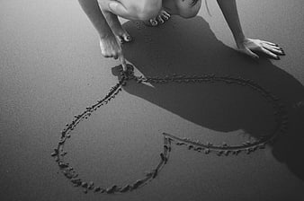 Woman Drawing Heart in Sand on Beach